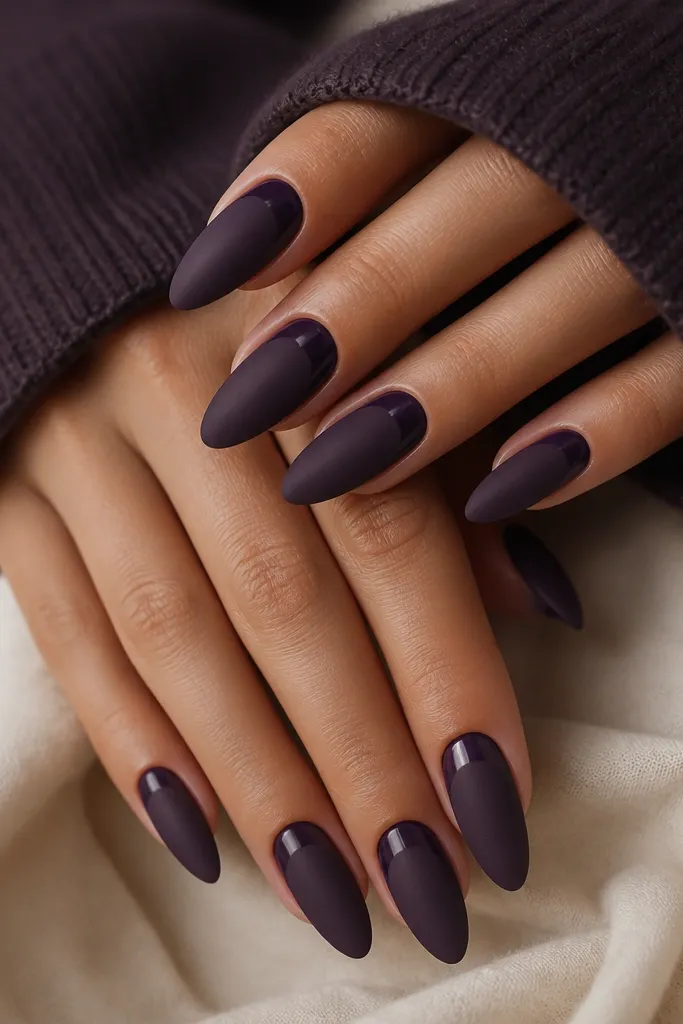 Almond nails in matte blackberry purple with a thin glossy crescent around each cuticle, like a halo, and a soft gradient shine only at the base.