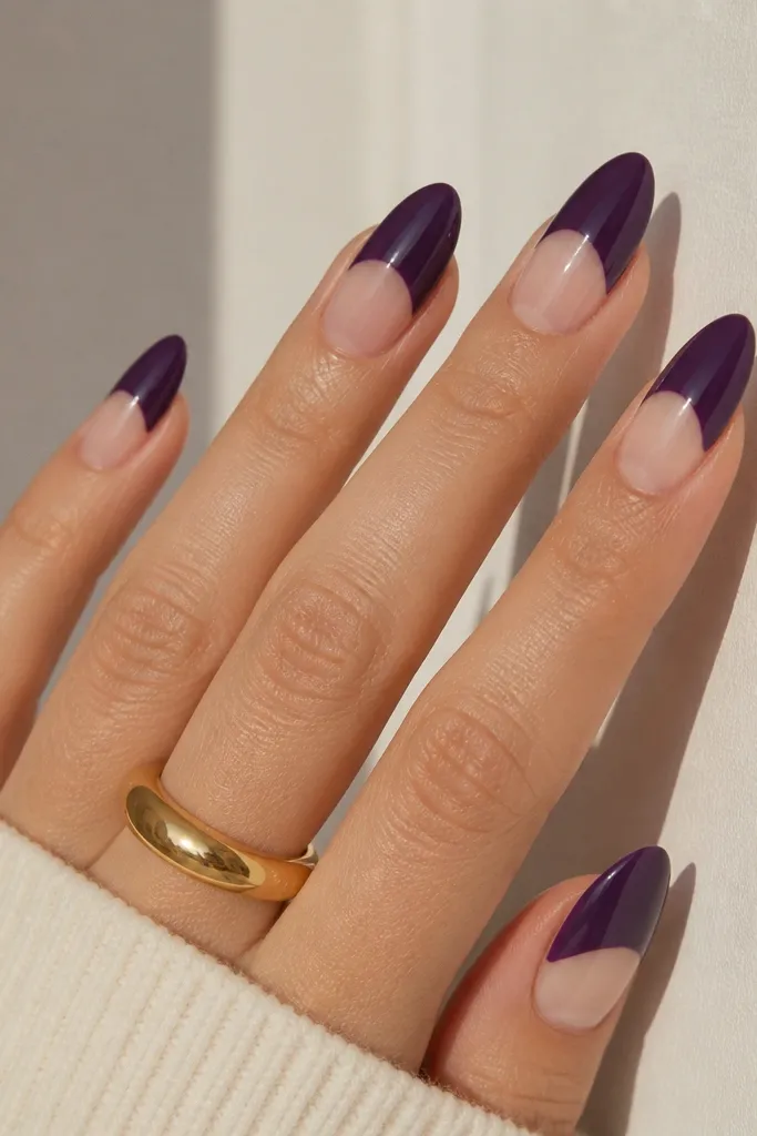 Almond nails with a dark purple half-moon only on the upper tip area, leaving a clear negative-space section near the base, creating a crisp two-tone look.