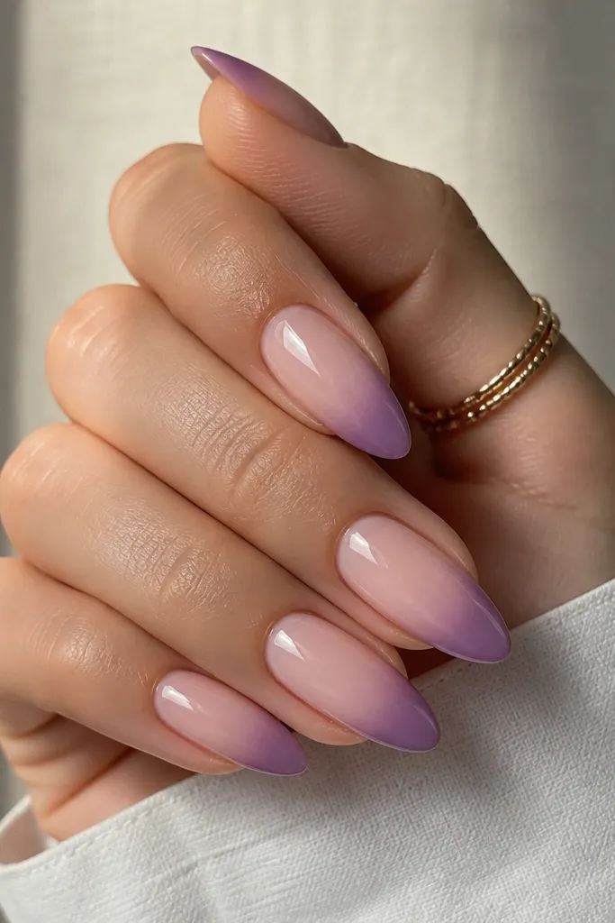 Almond nails with nude base and a purple French tip that fades softer toward the nail bed, with a smooth ombre transition and high gloss.