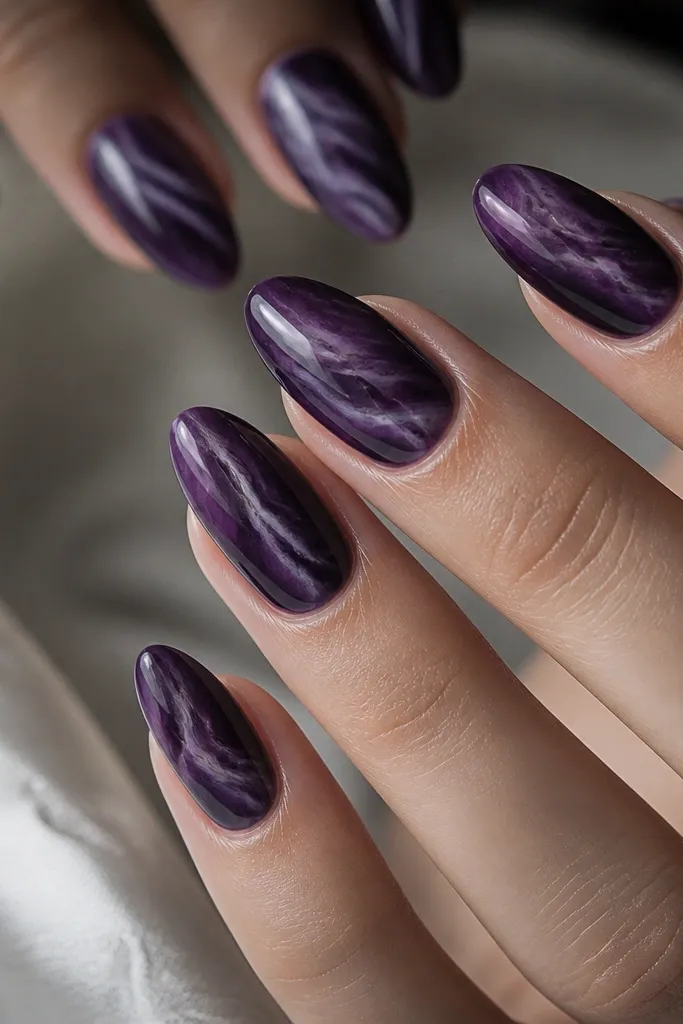 Dark purple almond nails with marbled streaks in lighter lavender and smoky plum, swiped in thin organic lines across the nail, glossy finish.