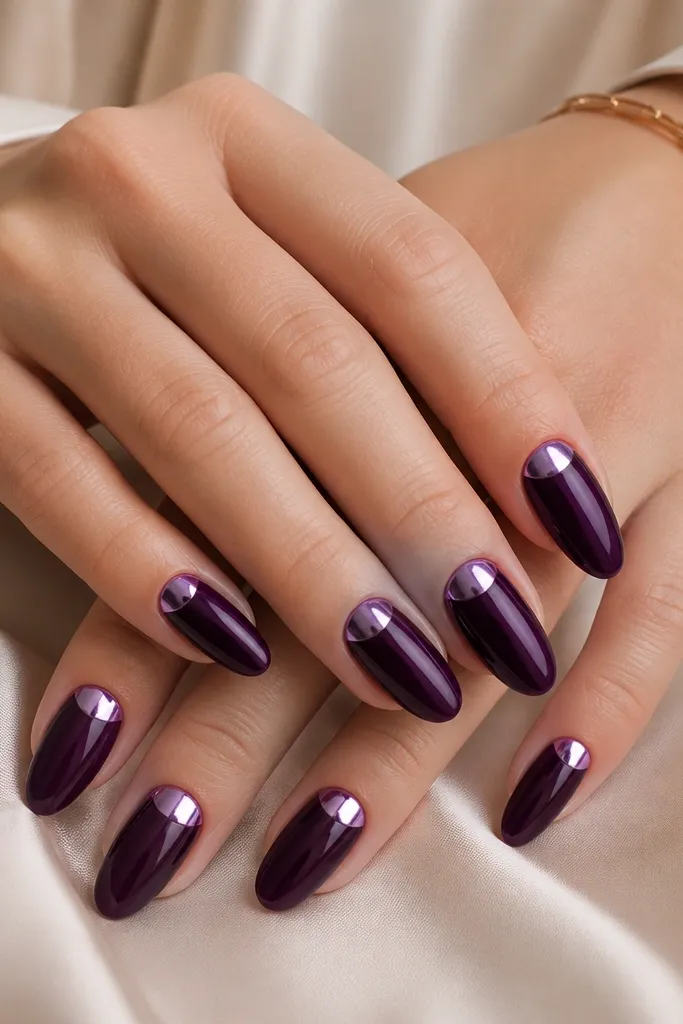 Glossy dark purple almond nails with a metallic purple chrome half-moon on the upper cuticle area, reflecting light like a mirror.