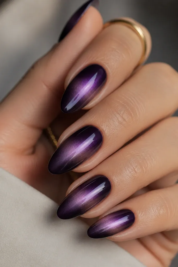 Almond nails with dark purple base and a soft lavender glow swipe coming from one side near the middle, fading as it reaches toward the opposite edge, glossy finish.