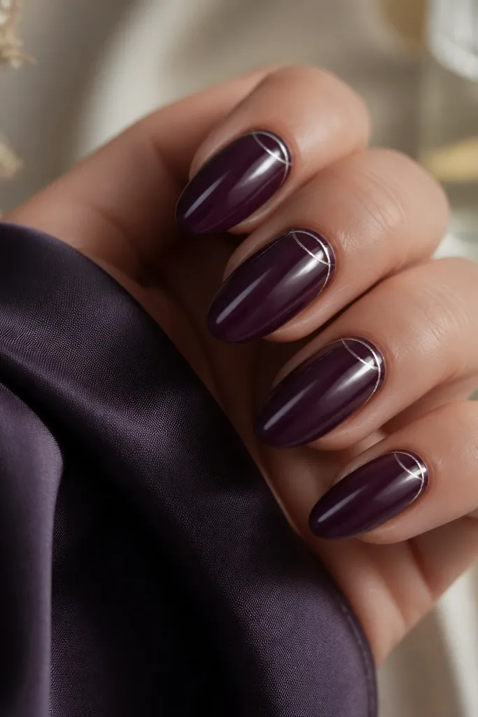 Dark purple glossy almond nails with thin silver crescent lines near the cuticle on each nail, like two curved strokes forming a partial ring.