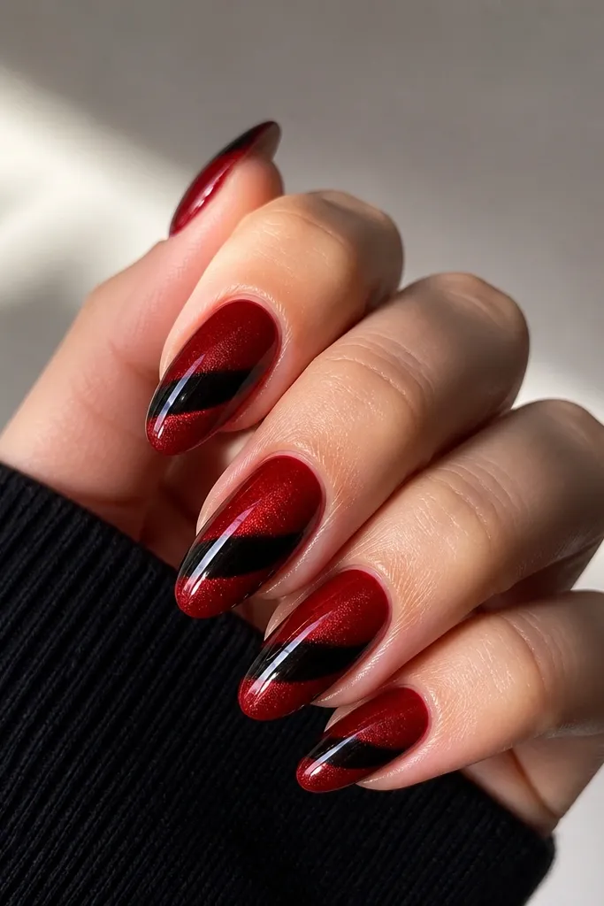 Medium almond nails. Base is glossy deep red. Each nail has a black cat-eye gel band across the center, pulled into a sharp line with a magnetic tool. The cat-eye band has a slight glow and a tiny crescent shine near the tip.