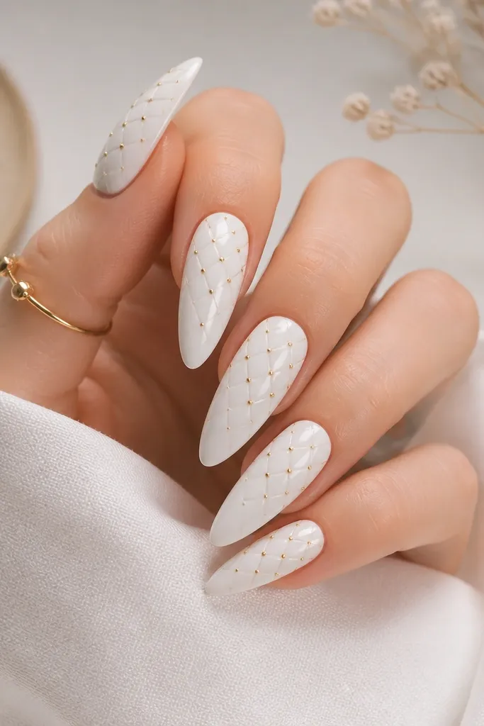 White glossy stiletto nails with a thin lattice grid across the surface. Small gold dots sit at the intersections, especially on the middle and upper half.