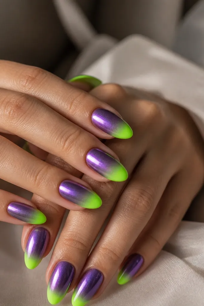 Medium almond nails with neon green tips blending into a deep purple base. Over the purple area, a mirror chrome fade creates a smoky metallic sheen. The neon tips remain solid and glossy.