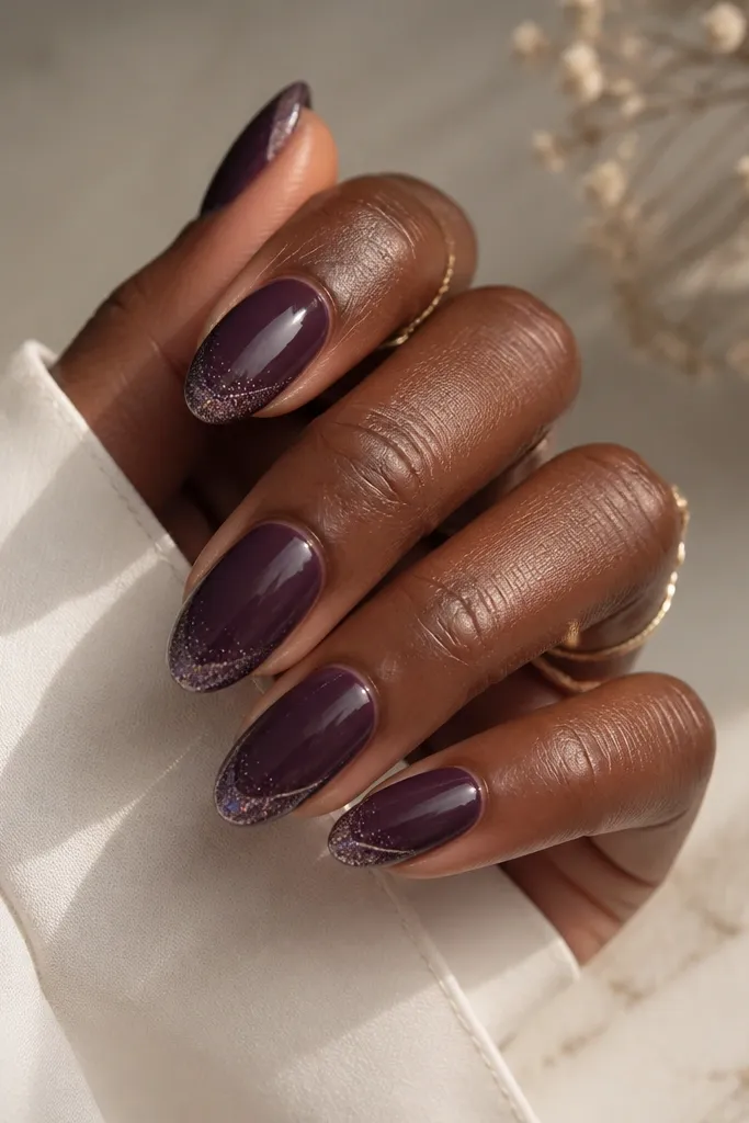 Medium almond nails with a dark purple base. The tip has a glitter fade that starts at the very edge, but a thin clear negative space line runs just above the glitter. Finish is glossy with a smooth clear line.