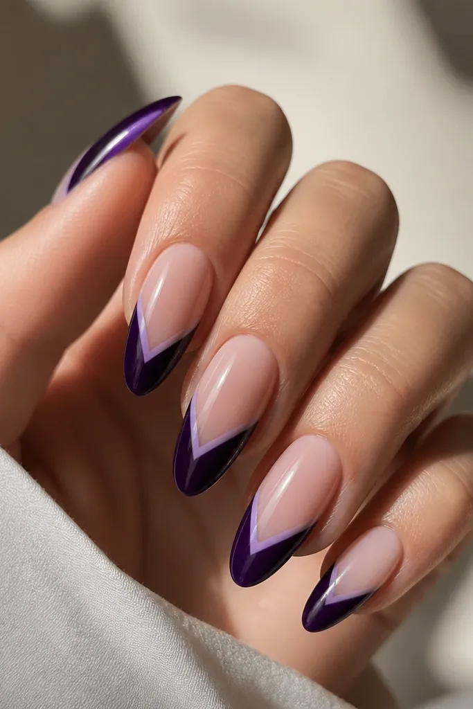 Long almond nails with deep dark purple tips shaped into a V at the center; a thin icy lilac outline traces the V edges, glossy finish.