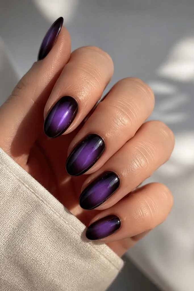 Medium almond nails with a smoky dark purple aura around the center; the edges fade outward, leaving a brighter purple glow in the middle, glossy finish.