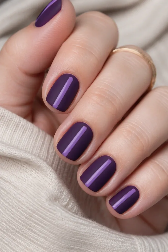 Short square nails matte dark purple; a single glossy candy stripe runs down the center from near cuticle to tip in a lighter purple, with crisp edges.