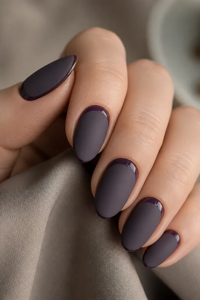 Short almond nails in matte smoky purple. A single glossy thin stripe runs along the cuticle line, creating a sharp contrast against the matte base.