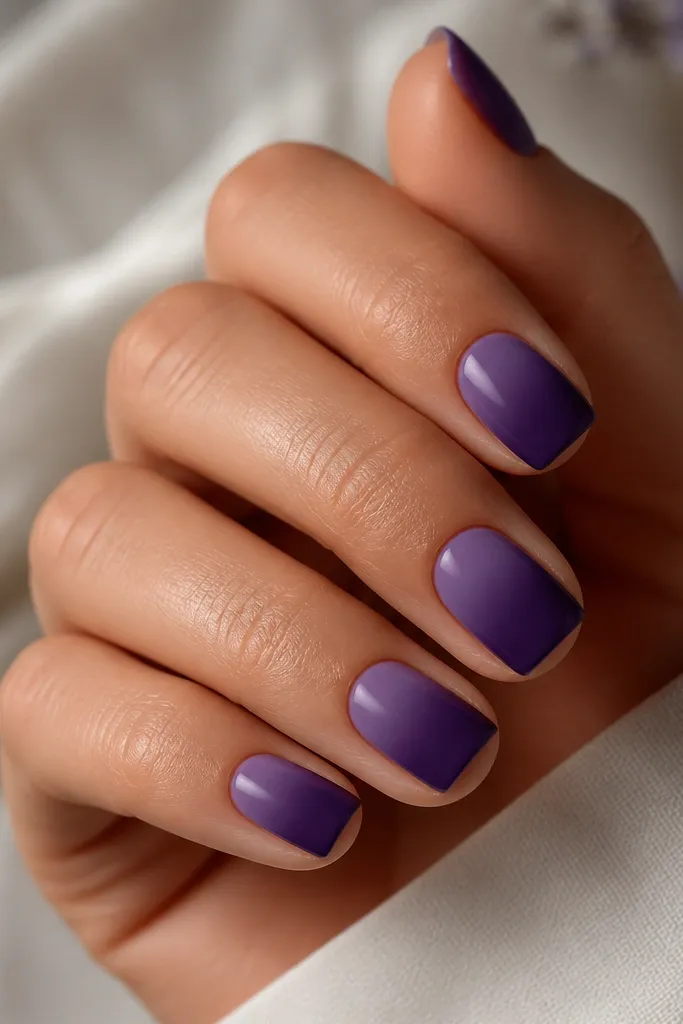 Short squoval nails with a soft ombre that fades from deep purple at the tip into a lighter, velvety purple near the cuticle. The gradient looks smooth like an airbrushed finish.