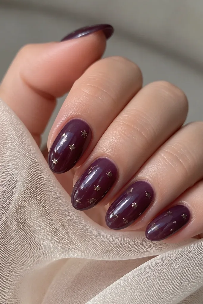 Short almond nails with a dark purple jelly base that looks translucent. Tiny star charms are embedded under the clear jelly effect, sparkling lightly.