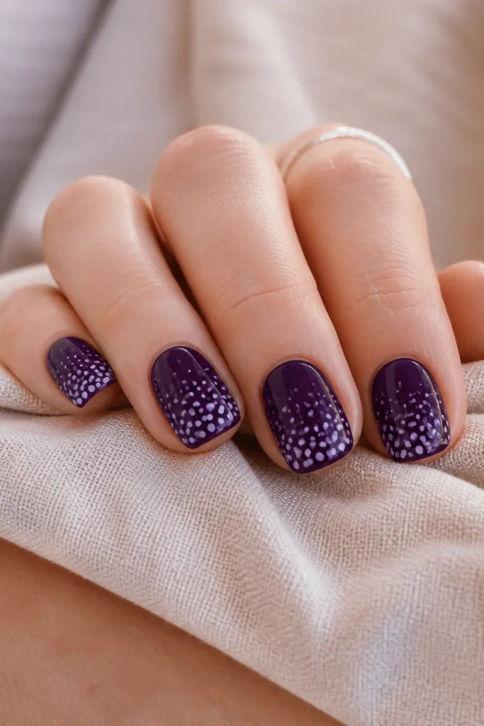 Short nails with dark purple base. Dots fade from larger and denser at the tip to smaller near the cuticle, giving a playful gradient effect.