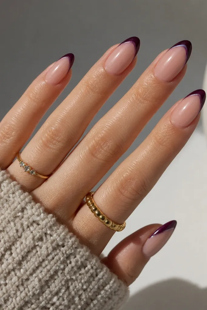 Medium almond nails with eggplant French tips. The tips have a razor-thin black line at the very edge, like a double outline. Nude base is semi-sheer pink.