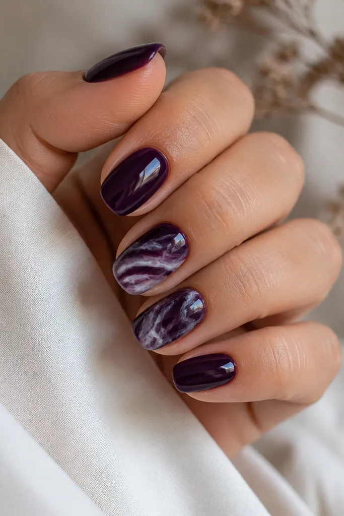 A glossy dark purple base on all nails. Two accent nails have thin white and soft lavender marble veining, with irregular swirls like natural stone.