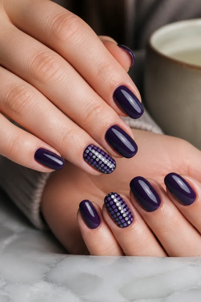 Glossy dark purple nails with one accent nail per hand featuring a tiny dot grid in lighter purple and silver. Dots are evenly spaced, arranged like a mini checker pattern.