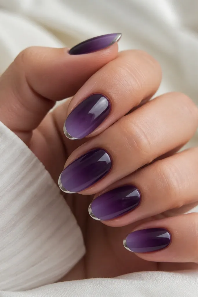 Nails in dark purple with tips that fade into a lighter purple. Along the very tip edge is a thin strip of silver foil, like a metallic border.