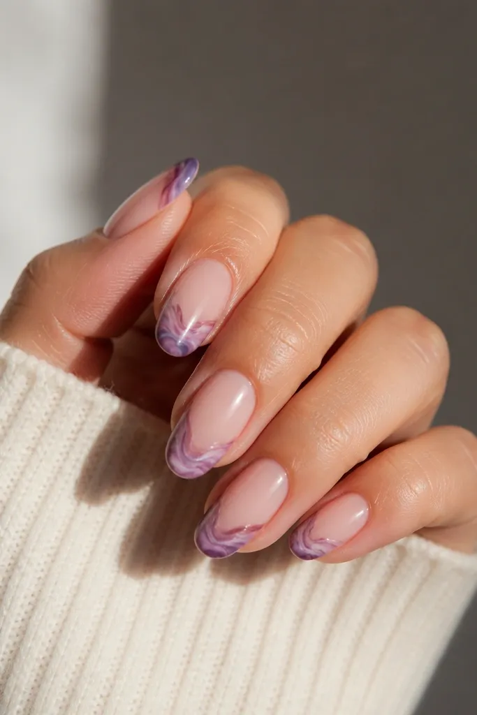 Nails have a nude-pink base with marble veining only on the tips. The tips are a mix of plum and soft lavender swirls.