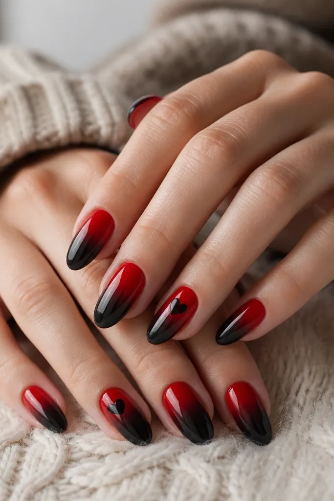 Nails with a smooth red-to-black ombre: red near cuticles fading into deep black tips; ring fingers have a small black heart silhouette over the red area.