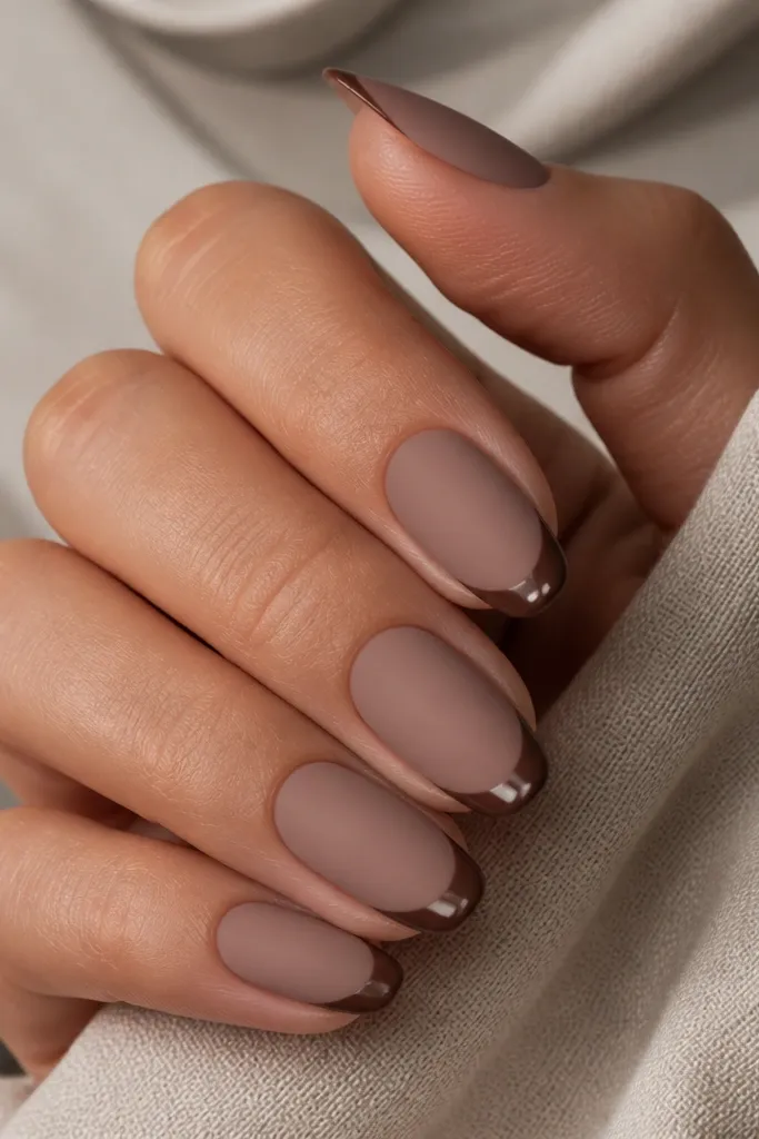 Nails have a matte mocha nude base. The French tips are glossy mocha brown, creating a finish contrast. The overall look is smooth with a sharp smile line.