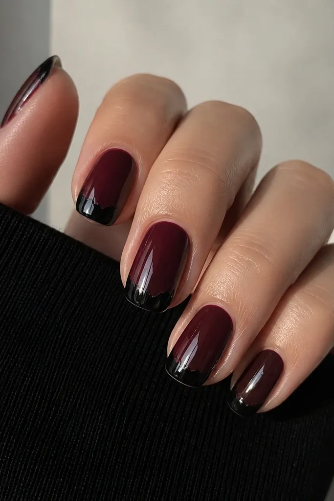 Nails painted deep black-cherry red with glossy shine. A French tip sits on top in black, but the border looks torn and uneven, like a jagged paper edge. Each nail has a slightly different torn shape.