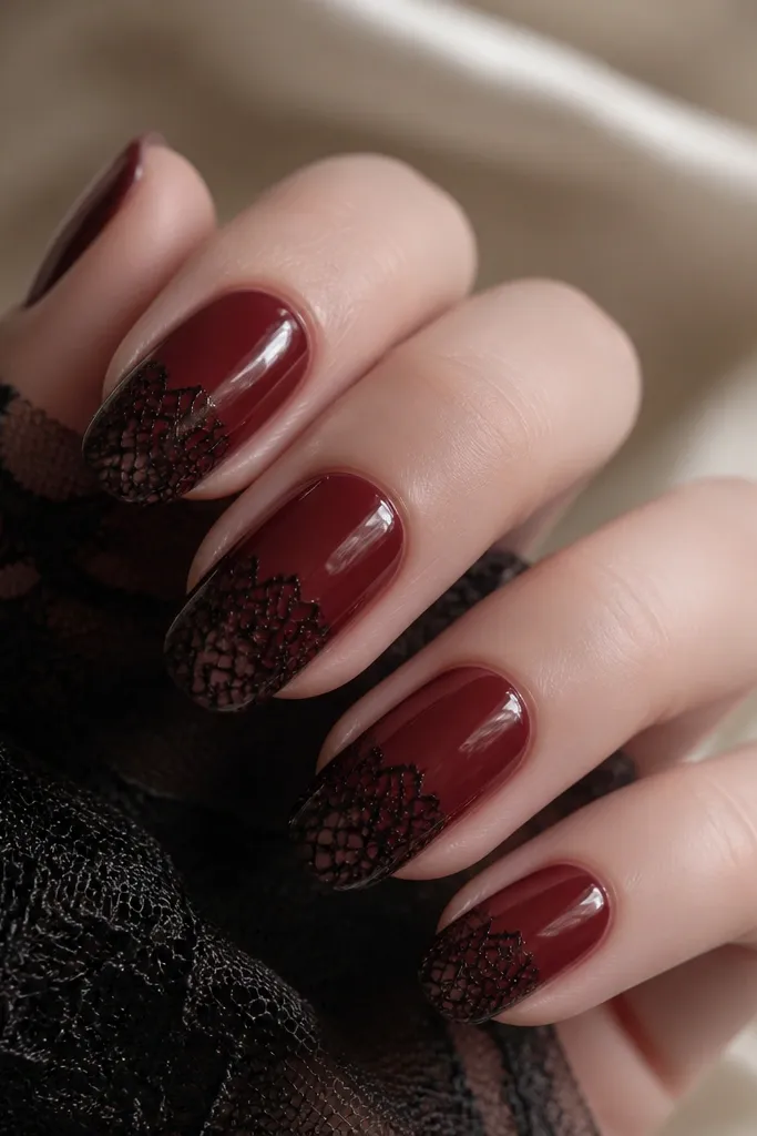 Oxblood glossy nails with black lace pattern concentrated at the tips. The lace looks like thin mesh lines and small loops, like a stencil overlay. The rest of each nail stays smooth and red.