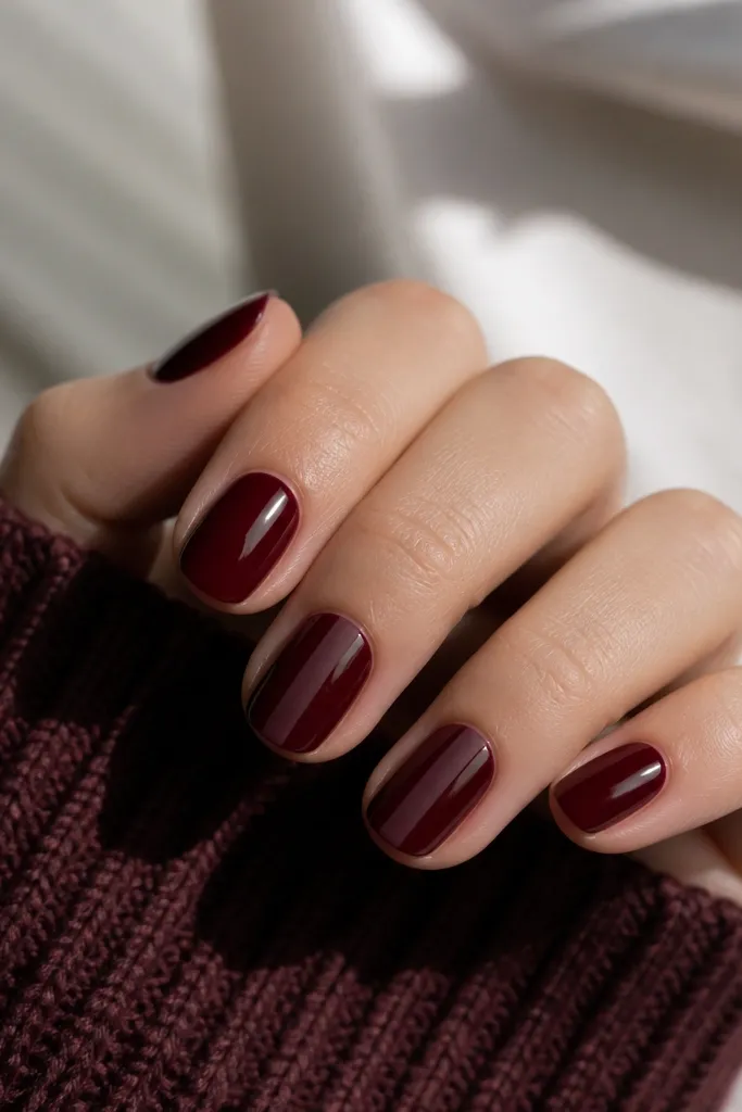 Short nails in deep oxblood red with high gloss. On two nails, there is a single vertical stripe near the center in matte finish, while the rest of the nail stays glossy. The stripe is clean and straight.