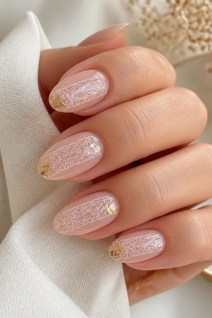Medium almond nails. Base is sheer pink. One nail set has white lace stamping pattern across the middle. In two corners of the stamped area, there are tiny gold foil accents. Glossy finish.