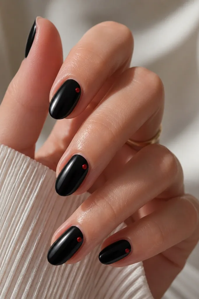 Most nails are solid glossy black. Each nail has exactly one small red dot near the sidewall close to the middle, like a tiny accent jewel.
