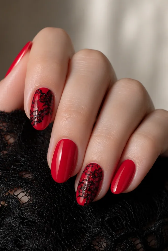 Nails in glossy red across most fingers. On the index and ring fingers, there is black lace-like line art near the center and edges, resembling a floral net pattern. Other nails stay solid red with no extra art.
