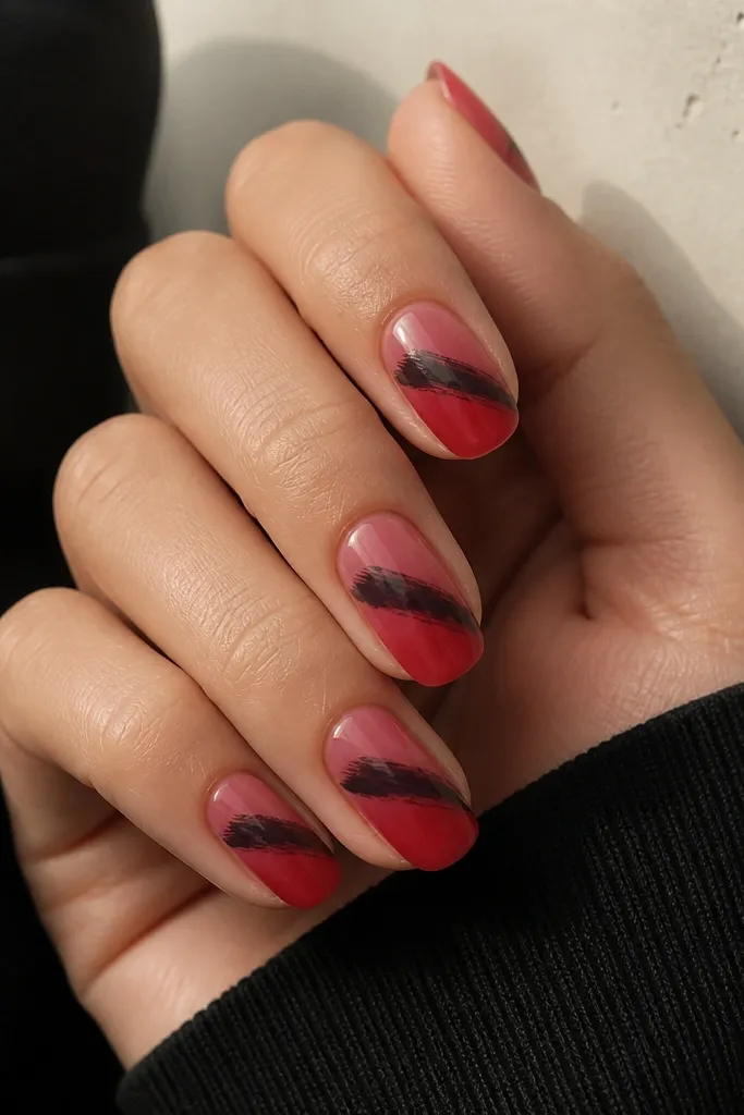 A soft red gradient on each nail, fading from deeper red at the tip to lighter red near the cuticle. Over the gradient, there is a single thick black brushstroke slanting diagonally across the middle. The black stroke has visible brush texture but looks intentional.