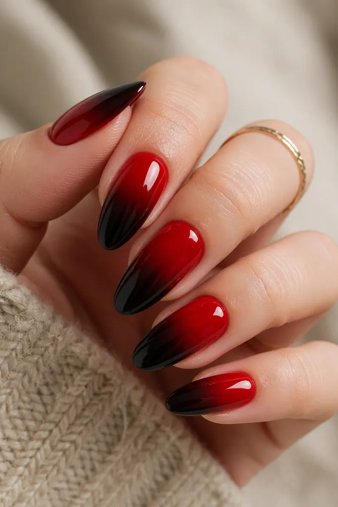 Nails show a smooth ombré from bright red at the cuticle fading into black at the tips. The gradient is soft and blended, with a glossy finish. No other art is added.