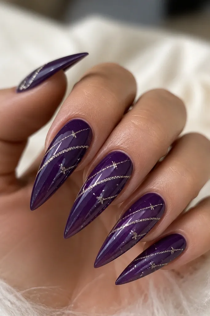 Stiletto nails with a dark purple base; thin curved lines in silver glitter thread across the nail like shooting stars, with small dot accents and a glossy finish.