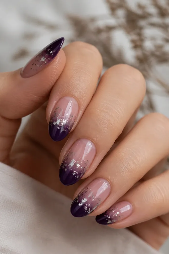 Medium almond nails with deep purple jelly ombré from tip to sheer center; silver leaf dust is sprinkled lightly and concentrated near the tip transition, glossy finish.