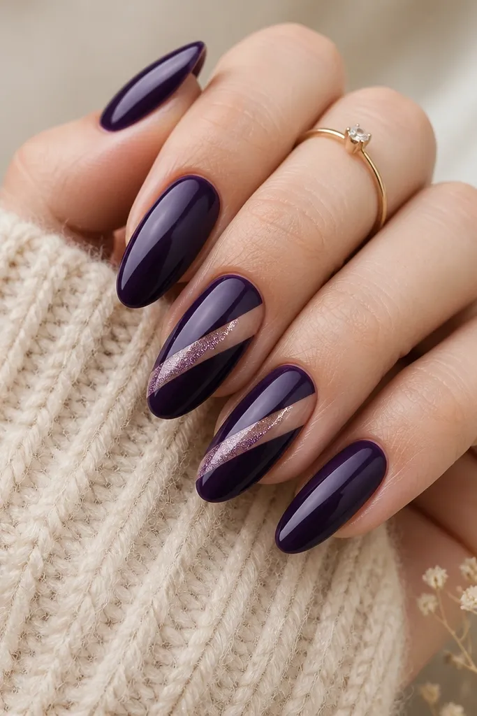 Almond nails with deep purple solid color; two accent nails have a diagonal glitter stripe running from lower left to upper right, with a clean negative-space edge.