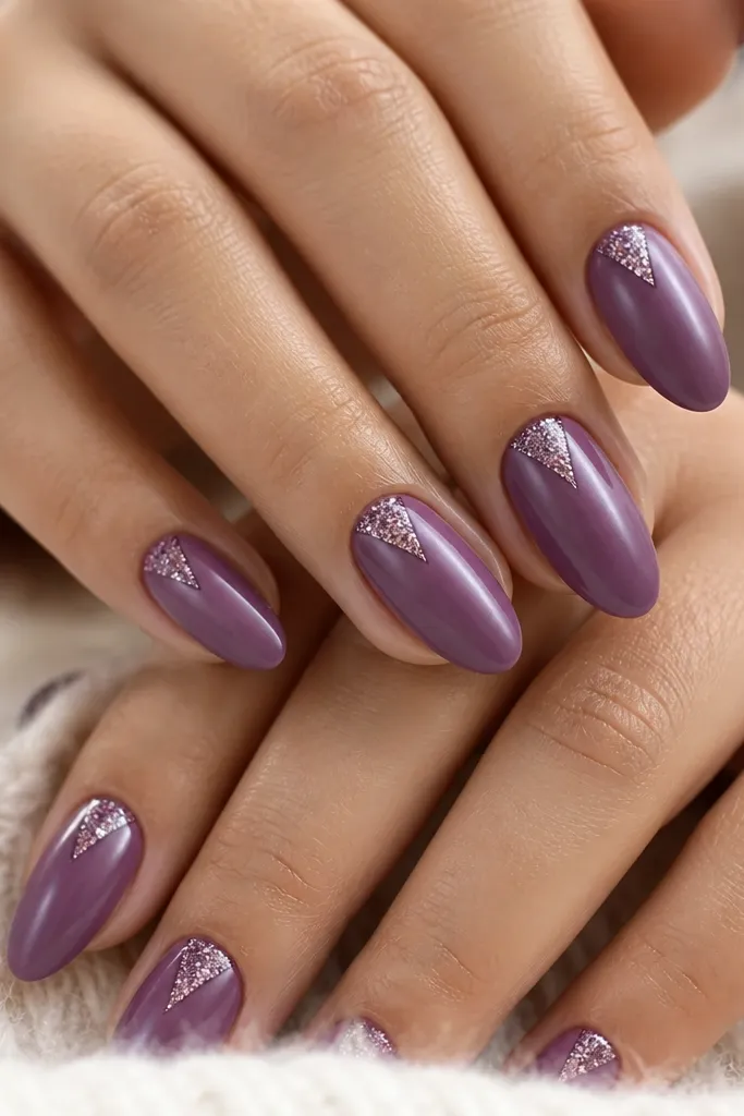 Medium almond nails with satin-finish violet purple; a V-shaped glitter design sits at the cuticle pointing upward, centered on each nail, glossy topcoat.