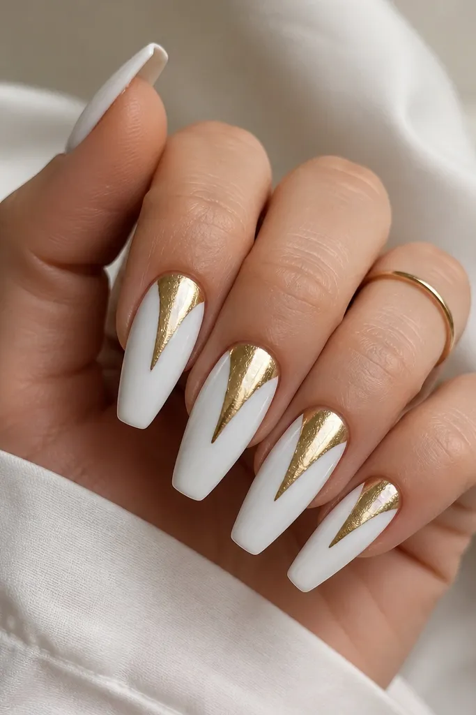 Medium coffin nails in glossy opaque white. A single gold foil line starts near the cuticle and drips downward in a controlled V shape on each nail. The foil is metallic and reflective.