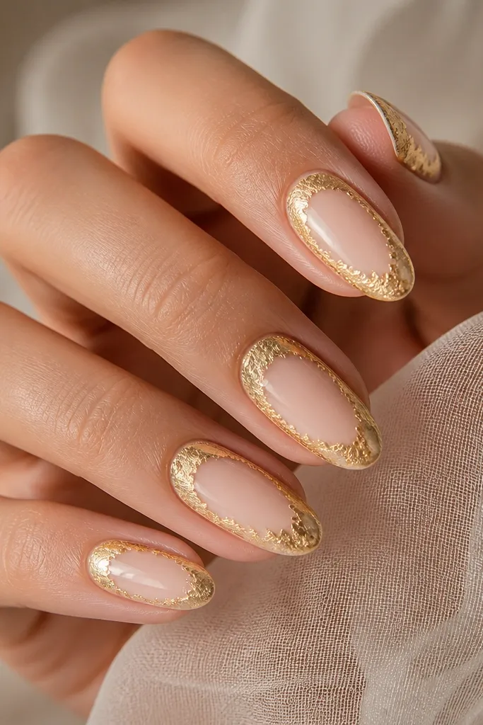 Medium oval nails with a white negative-space center. The edges of the nail are framed with gold foil like a picture frame, leaving the middle mostly natural nail or sheer nude. Gold foil is concentrated along the perimeter.