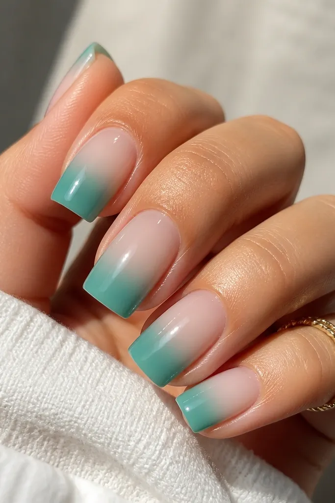 Square nails with seafoam ombre that fades from deeper teal-green at the tip to sheer near the cuticle. Glossy finish reflects light with a smooth transition.