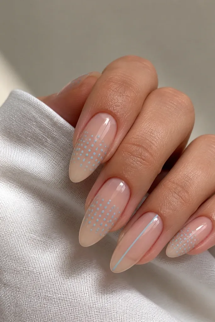 Almond nails with a glossy clear base and a light sky-blue micro dot pattern across the middle third; one nail has a single thin blue line down the center.