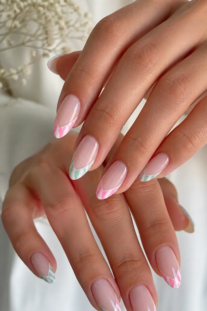 Almond nails with a sheer base; candy stripe tips in mint and bubblegum pink alternating diagonal lines, with a thin white border on each striped tip.