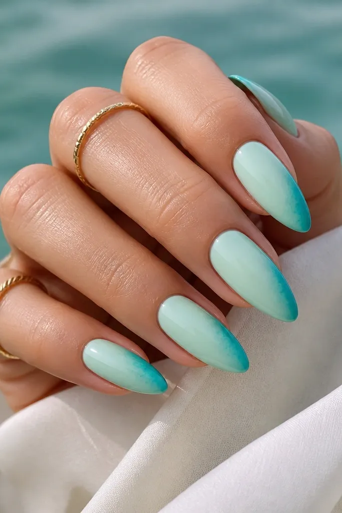 Almond nails with a pale mint sea-glass base and a turquoise fade concentrated along one side near the tip, with glossy finish.