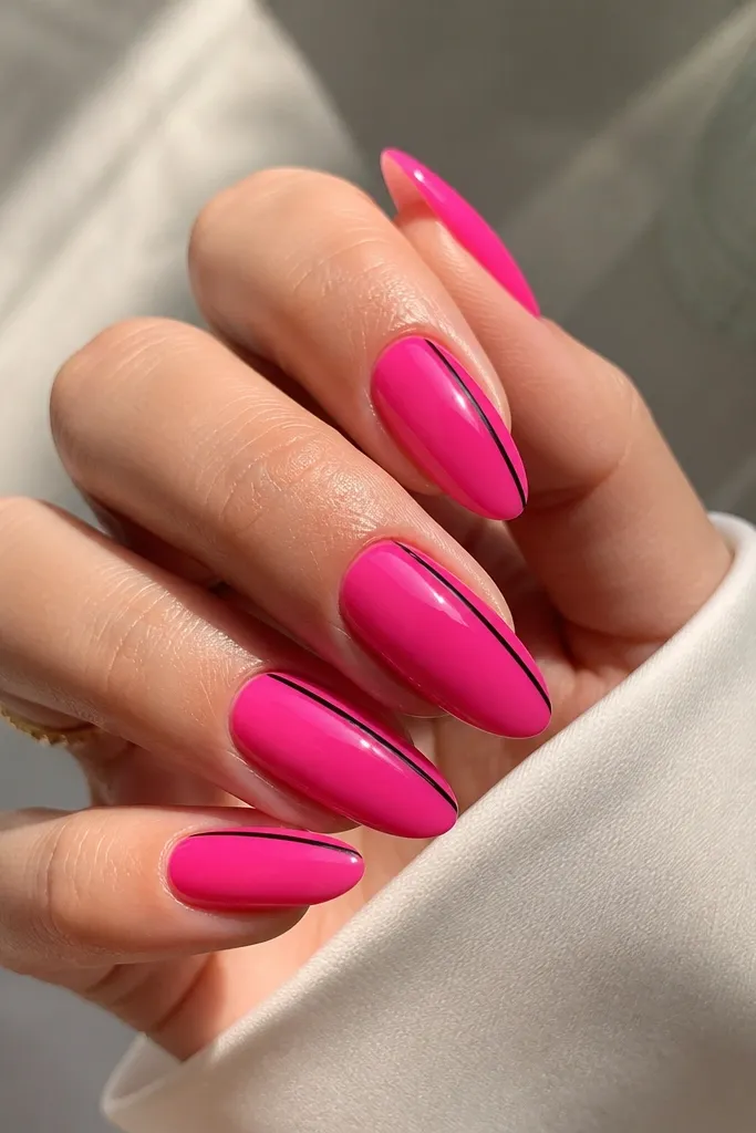 Almond nails in glossy hot pink with a single thin black stripe running vertically along one side of each nail.