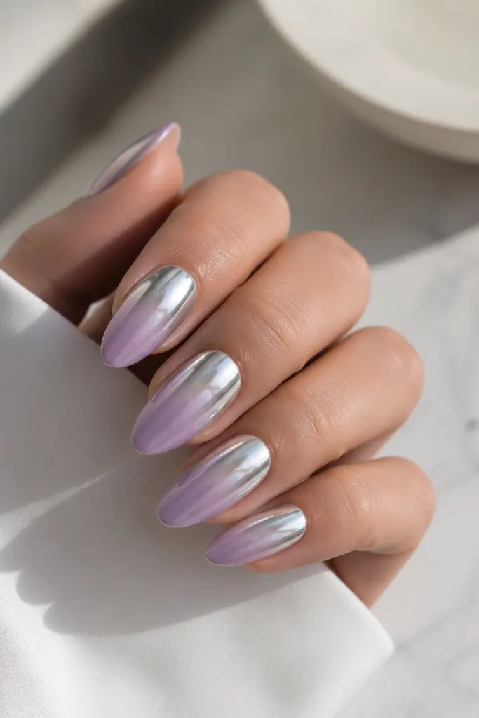 Almond nails with glossy lavender base; the upper half of each nail has a mirror silver chrome effect, fading slightly into the lavender.