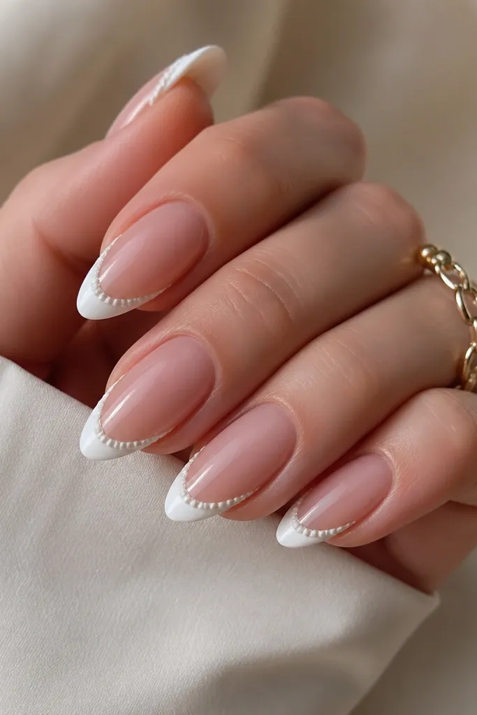 Almond nails with a classic French tip. The white French tip has a thin pearly shell border along the outer side, made from small curved ridges, with a glossy finish.