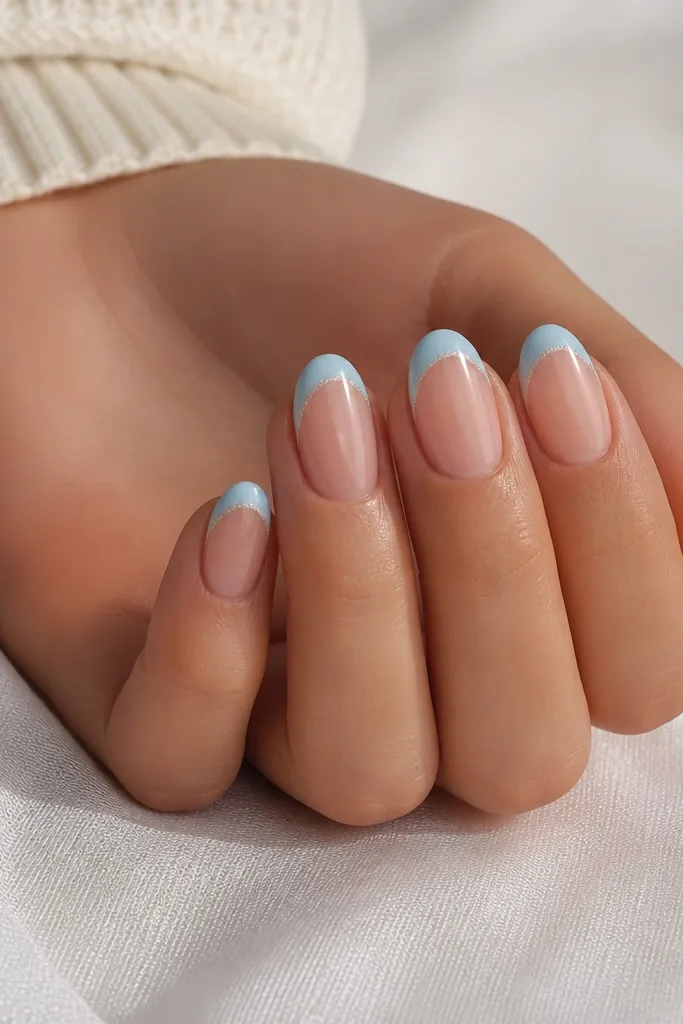 Nude base nails with baby blue French tips. Only the smile curve area has a micro glitter overlay, creating a subtle sparkle line.