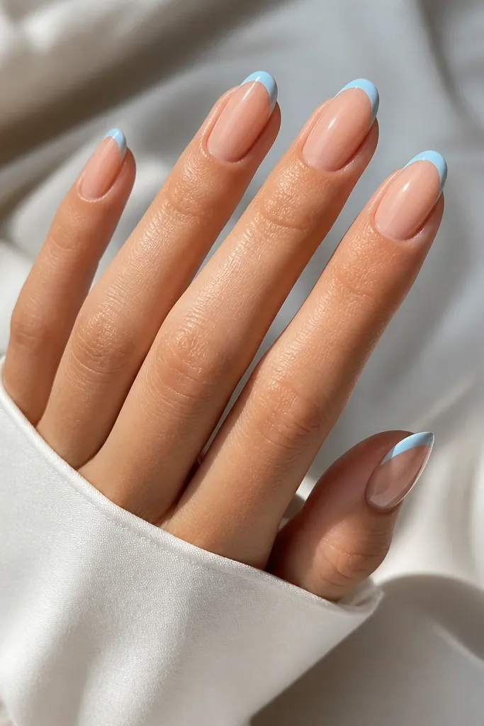 Nude base nails with baby blue only along the outer edge of the French tip. The center of the tip is nude, creating a thin outline effect with glossy shine.