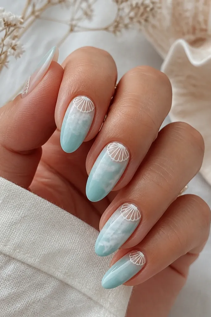 Medium almond nails with aqua marble swirls over a milky base. Along the cuticle line, a thin white shell border pattern repeats like scallops.