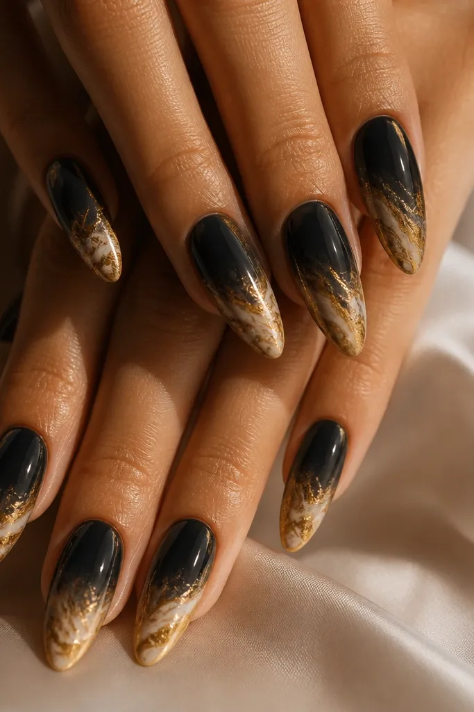 Almond nails with soft black smoky base. The tips have a gold marble pattern with creamy tan and gold swirls, like polished stone. The transition from black to gold is blended, not a hard line.